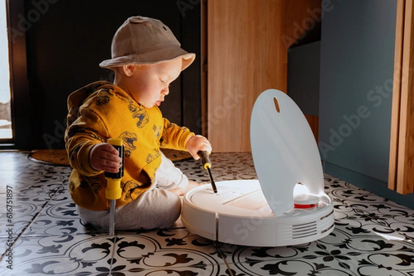 Obraz Baby on the floor with robot vacuum cleaner. Child repairs and play with robot vacuum cleaner. Home appliances for family with kids that make life easier for mother.