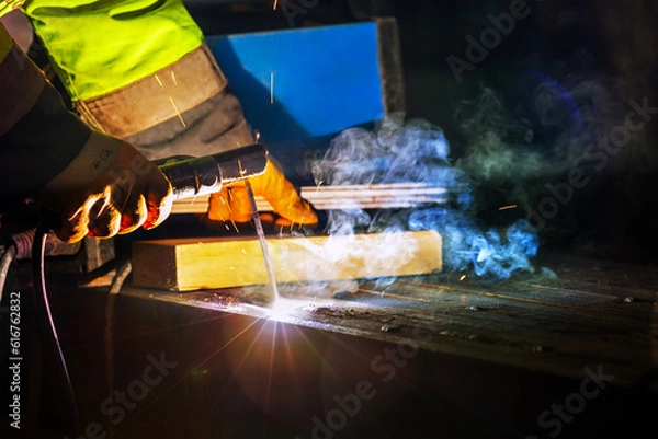 Fototapeta Welder is welding with shielded metal arc welding process to steel materials. Shielded metal arc (SMAW), also known as manual metal arc (MMA or MMAW), flux shielded arc welding.