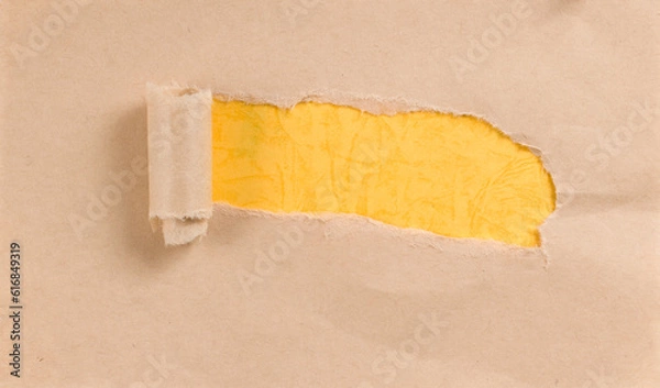 Obraz A torn piece of kraft paper revealing yellow paper underneath