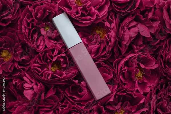 Fototapeta Nude pink lipstick on a background of red roses close-up with an empty space for text, copy space the concept of style and beauty, persistent cosmetics, a template for advertising a cosmetic product