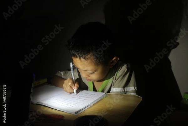 Fototapeta The boy studied accompanied by a candle