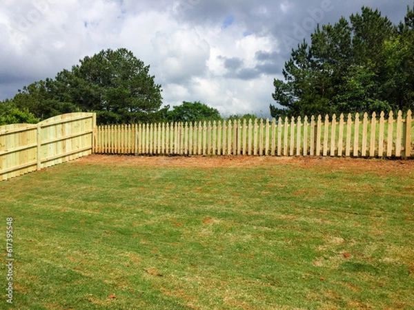 Obraz Wooden fence surrounds sloped backyard of new construction home.