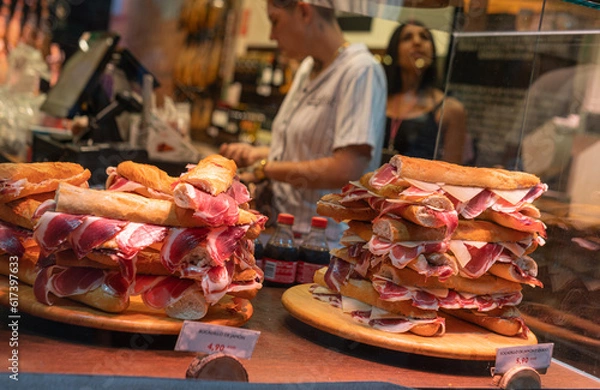 Fototapeta Spanish street food, Spanish sandwiches with sliced iberian cured ham jamon, bocadillo in showcase