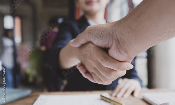 Obraz Business woman shaking hands and finishing up meeting at desk in office.