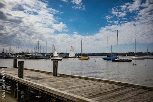 Fototapeta boats sit anchored at the end of a pier on a lake