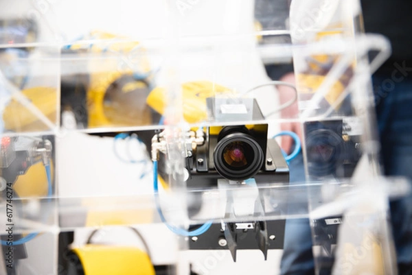 Fototapeta Machine vision. The manipulator arm uses a camera to observe and control objects in stock.