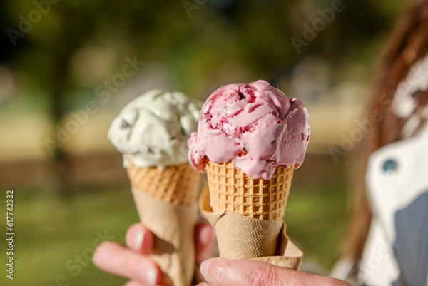 Obraz Two scoops of ice cream in hand. ice cream on a summer day outdoors.