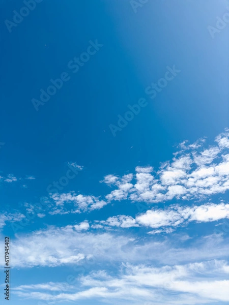 Fototapeta Blue sky with white clouds. Sunny spring, summer, fall, or winter weather. The photo is good for use as a background. Bright colors and good mood.
