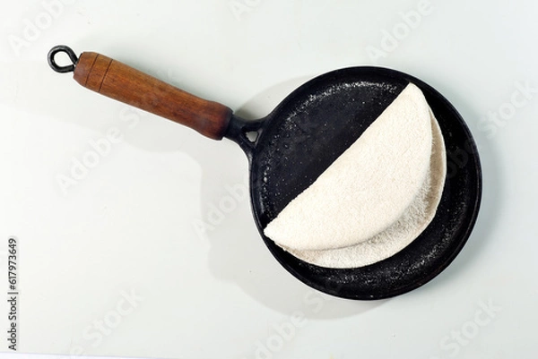 Fototapeta Tapioqueira  maker with a tapioca inside top view, Iron skillet, cast iron skillet, skillet for making tapioca (Frigideira de tapioca), on white background with selective focus, isolated