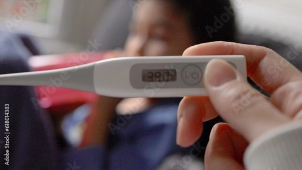 Obraz Close-up view of a thermometer showing a high temperature against a blurry background of a child