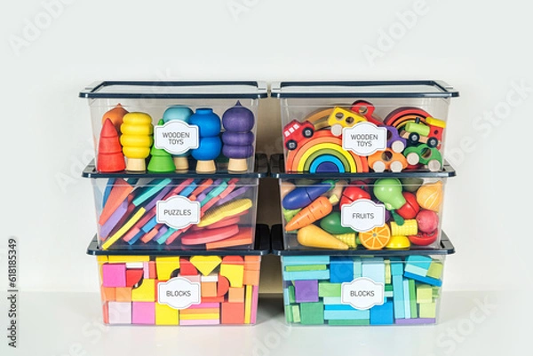 Fototapeta Transparent plastic containers with various children's toys on shelves. Storage box with label sticker with name title. Organizing and Storage Ideas in nursery.  Toys sorting system.