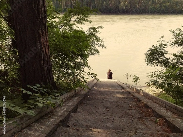 Fototapeta the person is sitting on the syairs by the river