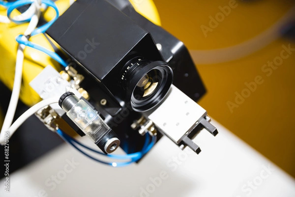 Fototapeta A close-up robotic arm equipped with a computer vision lens for processing video using artificial intelligence.