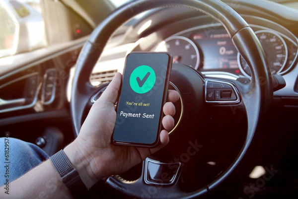 Fototapeta Man is paying online with mobile phone inside a car.