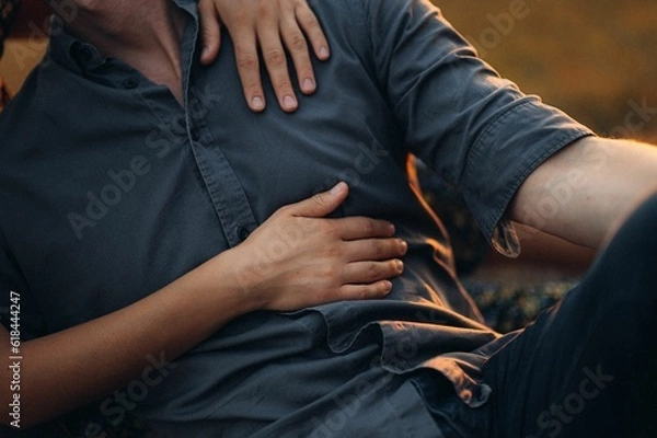 Fototapeta Szczęśliwa młoda para pozuje na pokrytej słońcu łące o zachodzie słońca.