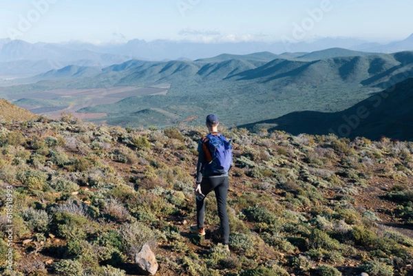 Fototapeta A man hiking in the mountains looking over a vast unexplored wilderness during an adventure hike.