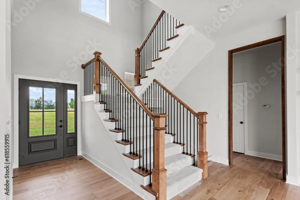 Fototapeta staircase in a house with stained wood rail, black spindles and end caps - white staircase, and carpeted, pattern runner. 
