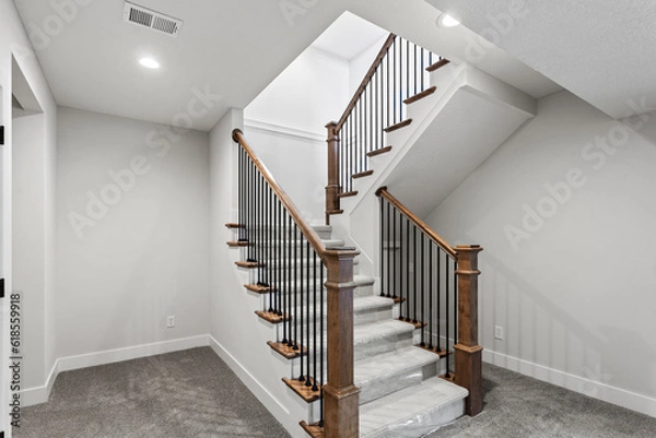 Fototapeta staircase in a house with stained wood rail, black spindles and end caps - white staircase, and carpeted, pattern runner. 
