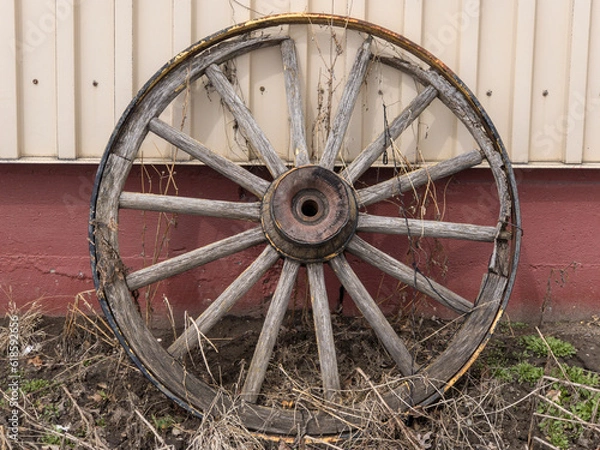 Obraz old wagon wheel leaning against a barn
