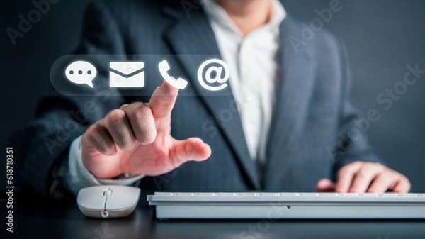 Fototapeta Businessman hand touching white virtual reality assistant interface mobile computer keyboard and mouse email mail phone web address and support chat icon. Customer care service representation concept.