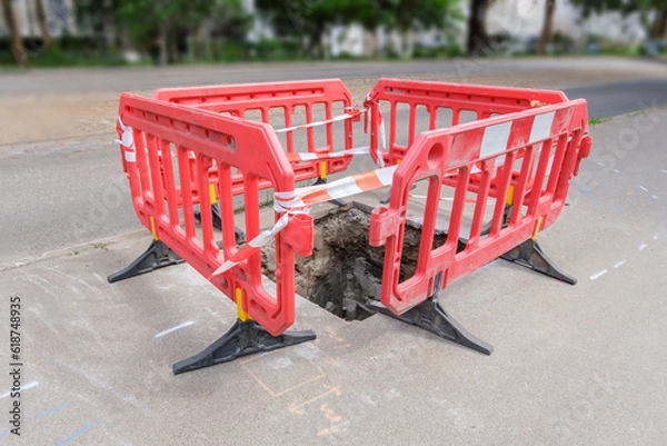 Obraz red plastic protective barriers for road works. barriers around pit on the road.