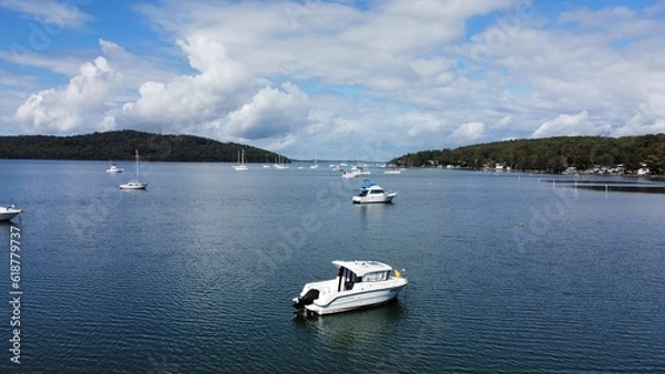 Obraz Scenic shot of a peaceful body of water, featuring small boats near the shoreline and a lush