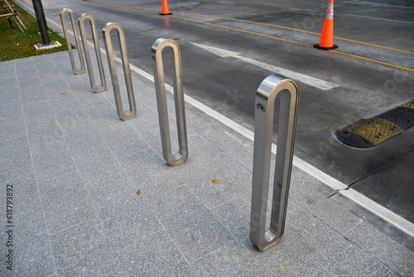Fototapeta Aluminum Bicycle parking rack or bicycle stand near the road side with bicycle sign,  a device to which bicycles can be securely attached for parking purpose . modern style for city.
