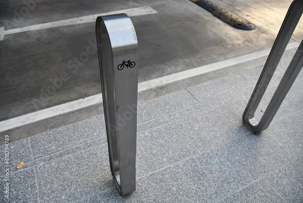 Fototapeta Aluminum Bicycle parking rack or bicycle stand near the road side with bicycle sign,  a device to which bicycles can be securely attached for parking purpose . modern style for city.