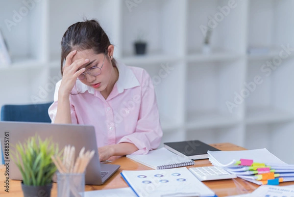 Fototapeta Sharing good business news. Attractive young businesswoman Used the laptop with document and smiling while sitting at her working place in office.