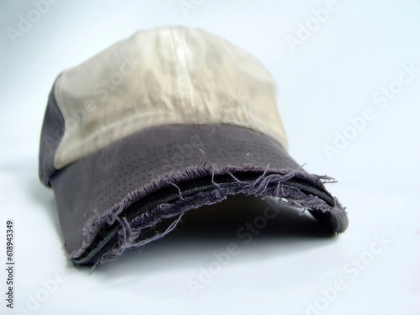 Fototapeta Old, worn and frayed baseball hat on solid background