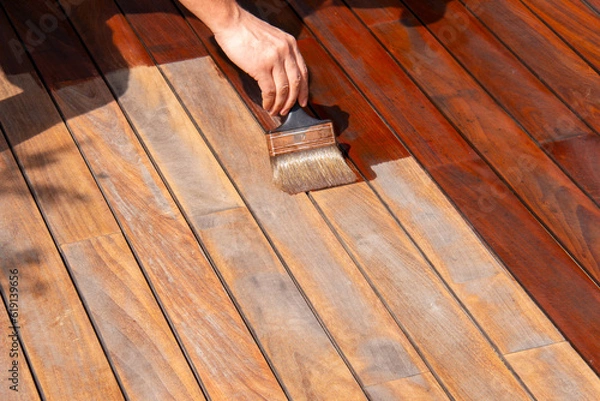 Fototapeta Ipe deck refreshing, worker's hand is oiling terrace decking with a painting brush