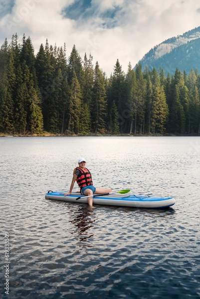 Fototapeta pretty girl wear Life vest is resting and sunbathing on a surfboard after training