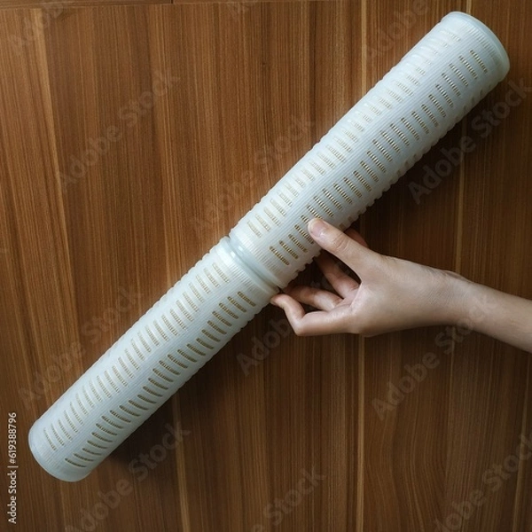 Fototapeta Hand holding Water Filter Cartridges on wooden background. Cartridge Filters use for water filtration and reverse osmosis