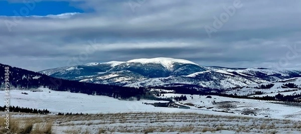 Fototapeta Scenic view of a mountainous landscape covered with a blanket of snow and lush evergreens