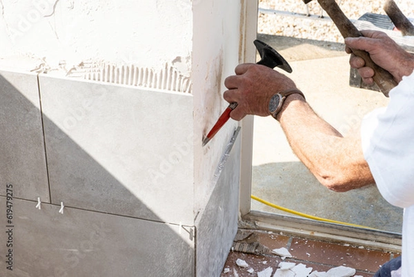 Fototapeta the mason prepares the wall with a chisel before laying a ceramic tile