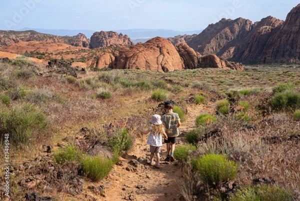 Obraz A small boy and a girl hiking in Snow Canyon, St. George, Utah, USA. Kids walking in red rocks.
