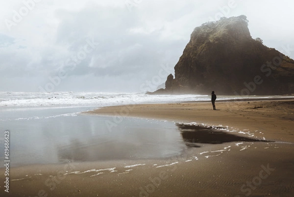 Fototapeta A shot of a model standing and looking into the distance on Piha beach in New Zealand