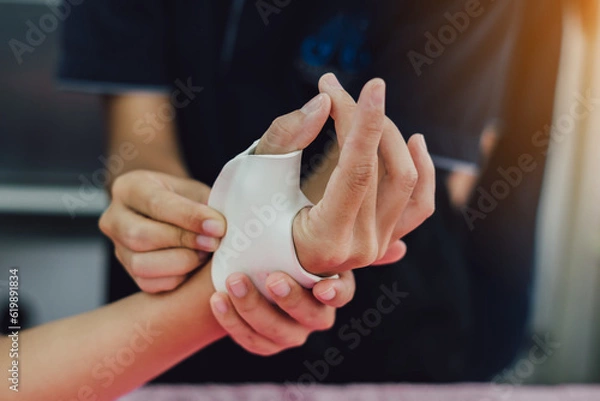 Fototapeta Therapist making asissistive device for immobilize patient hand. Splint service for hand injury rehabilitation of occupational therapy clinic.