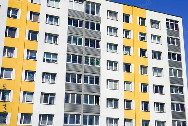 Fototapeta Renovated and insulated multistorey apartment building against a blue sky background