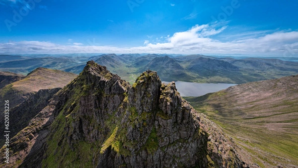 Fototapeta Breathtaking aerial view of a man standing on top of An Teallach mountain on a clear summer day in Scotland revealing the great wilderness.