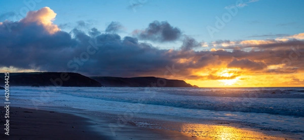 Fototapeta Dramatic sunset with waves breaking on Widemouth Beach in Cornwall, UK