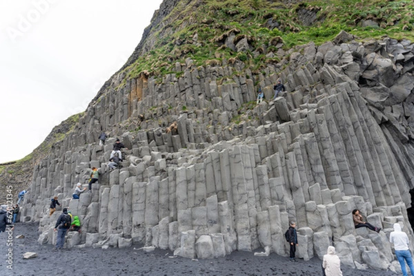 Fototapeta Reynisfjara Black Sand Beach, Iceland - 06.22.2023: People climbing on basalt columns on Reynisfjara beach