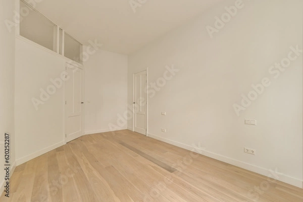 Fototapeta an empty room with white walls and wood flooring on the right, there is a door leading to another room