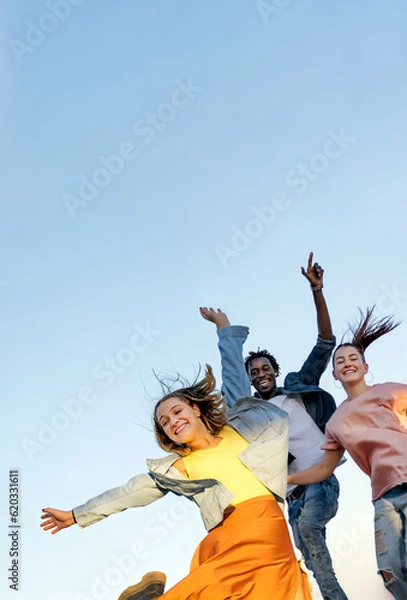 Fototapeta Group of happy multiracial  friends smiling and jumping over blue background - Concept of happiness, freedom, motion,  and friendship. 