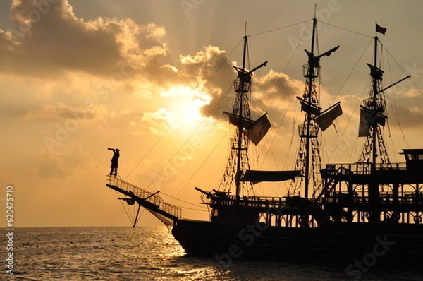 Fototapeta Historical ship and observing pirate at sunset.