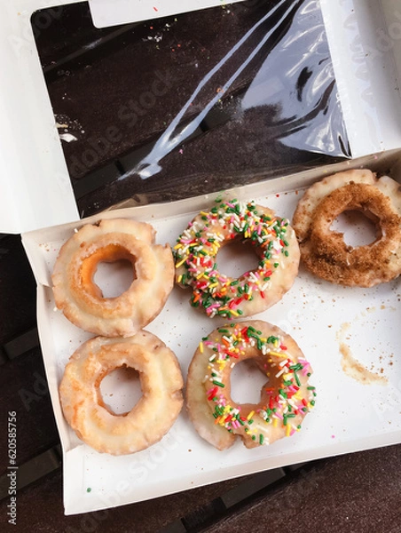 Fototapeta Donuts, box of assorted, store-bought old-fashioned sour cream doughnuts with sugar glaze, sprinkles and cinnamon sugar topping outside for picnic