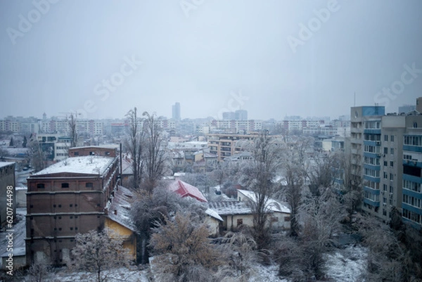 Obraz View of industrial and residential buildings in snow covered Bucharest during the winter.