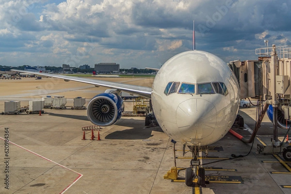 Obraz A Boeing 777-200 passenger plane being loaded with baggage at the airport
