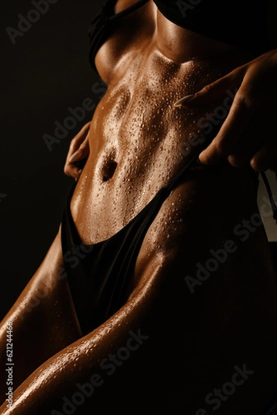 Obraz athletic figure without underwear of a sexy girl belly with drops of sweat and water in the gym in a low key