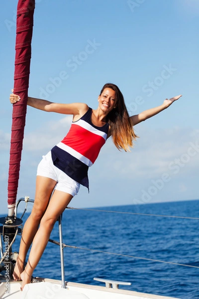 Fototapeta Happy woman on the bow of a Sail Boat with arm raised. Copy space